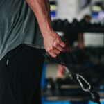 man in gray t-shirt and black pants holding black corded headphones